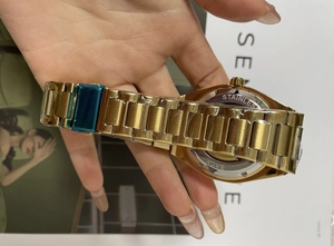 Macro detail of the stainless steel case back and golden metallic strap of the watch