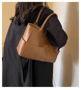 Close-up of brown woven leather tote bag texture and top handles on shoulder