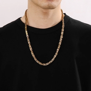 Close-up of a two-tone gold and silver Byzantine chain necklace on a male model