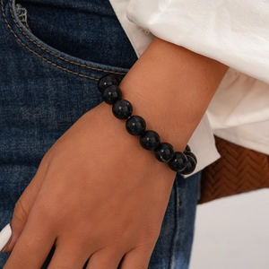 Close-up of minimalist 10mm black bead bracelet on wrist with high-gloss finish