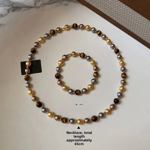 Détail de parure en perles d'oeil de tigre avec fermoirs magnétiques sur plateau blanc