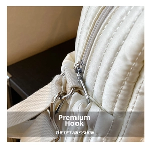 Detailed close-up of the silver metal swivel hook and quilted fabric on the diaper bag