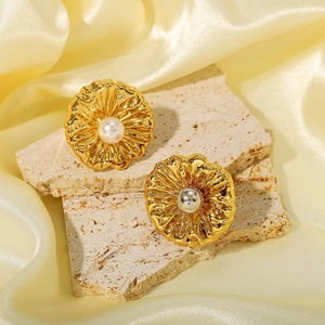 Elegante goldene Blumenohrringe mit weißer Perle auf einem minimalistischen beigen Steinsockel