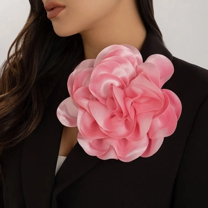 Detailed close-up of a large pink satin fabric rose brooch pinned on a black blazer
