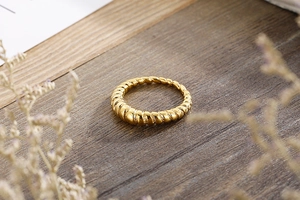 Close-up of golden croissant textured ring on elegant dark wooden pedestal with flowers