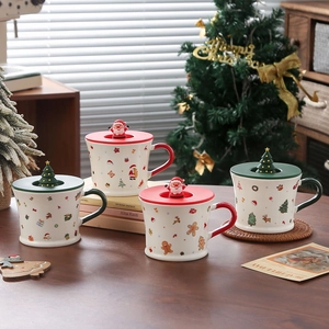 Close-up of Christmas ceramic mugs with 3D Santa and tree lids on a cozy wooden table