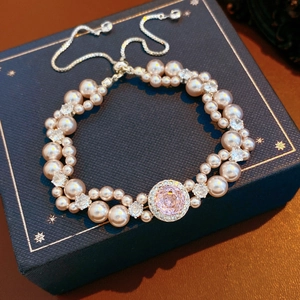 Dettaglio del bracciale di perle con pietra a cuore rosa e catena d'argento regolabile