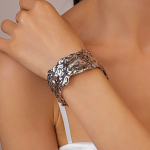 Close-up of wide silver cuff bracelet with liquid metal ripple texture on female model