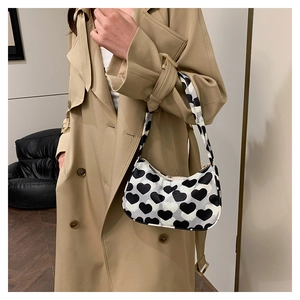 Vue détaillée du sac à bandoulière en toile avec motif de cœurs noirs et blancs et zip