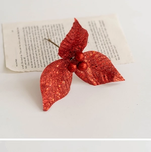 Detail of red glitter Christmas berry pick with leaves over vintage book pages