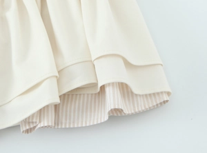 Détail de l'ourlet superposé montrant tissu tissé crème et doublure rayée brune