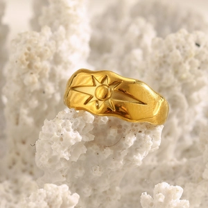 Macro shot of 18K gold plated wide starburst ring on a natural white coral stone background