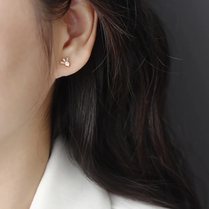 Close-up of a gold s925 silver stud earring featuring square zircon stones on an earlobe