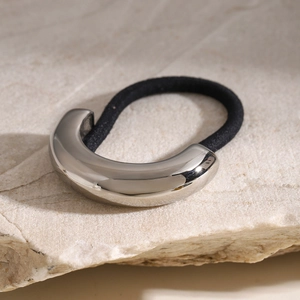 Close-up of sleek silver metal buckle on a black high-elastic hair tie on stone