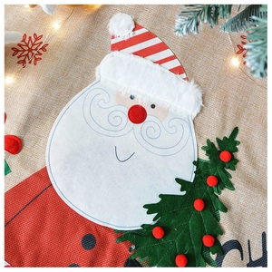 Detail of embroidered Santa and Christmas tree patterns on linen fabric with warm festive lights
