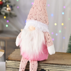 Detail eines rosa Weihnachtsgnoms mit Pailletten und langen Beinen auf Holzbox
