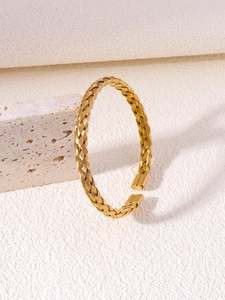 Detailed macro view of golden twisted texture cuff bangle with polished ends