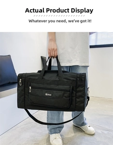 Detail of a black nylon travel bag featuring reinforced handles and adjustable shoulder strap