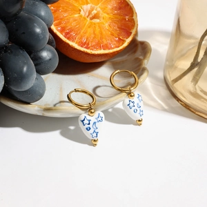 Dettaglio di orecchini a cuore in ceramica con stelle dipinte a mano e oro 18 carati