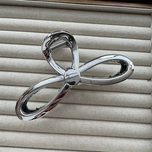 Detail of silver metallic bow hair claw clip with a high-gloss electroplated finish