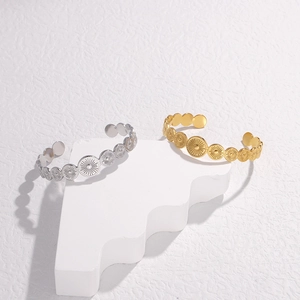 Detail of gold and silver open bangles with engraved sunburst patterns on circular discs