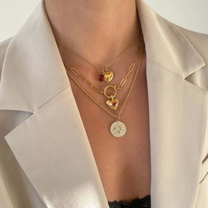 Close-up of triple-layered gold necklaces with heart, ruby and sun medallion pendants
