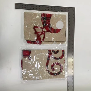 Detailed view showing a linen Christmas gift bag with red plaid trim and a white pompom