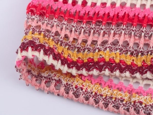 Detail of colorful crochet knit fabric with pink and yellow stripes and scalloped edges