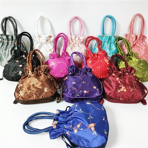 Macro view of assorted satin drawstring buckets with floral ethnic embroidery