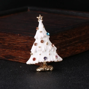 Close-up of white enamel Christmas tree brooch with colorful rhinestones and gold base