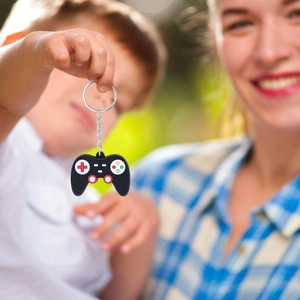 Cartoon game controller keychain with colorful buttons held by a child in natural light
