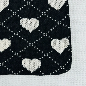 Close-up of heart and diamond knit pattern showing detailed fabric texture and ribbed edge