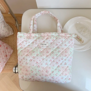 Detail of pink floral quilted tote bag with diamond texture and simple wish label