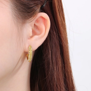 Close-up of gold-plated C-shape hoop earrings with micro-paved sparkling zircon stones