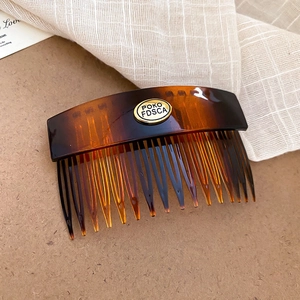 Close-up of tortoise shell pattern acrylic hair comb with elegant gold metal logo plate