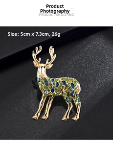 Detail of golden reindeer brooch with colorful enamel work, measuring 5cm x 7.3cm