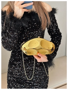 Detail of a gold mirrored metal clutch bag with an irregular stone-inspired design and chain
