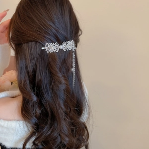 Detail of silver tassel hair clip with rhinestones and pearl on model wavy hair