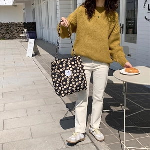 Foto de estilo de vida de un bolso tote de pana negra con flores y etiqueta tejida