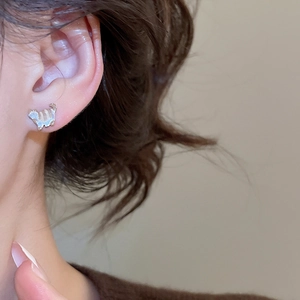 Close-up of cat-shaped silver stud earring worn on ear showing fine enamel details