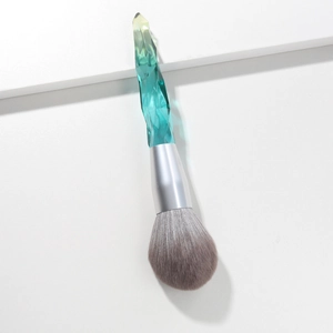 Macro view of emerald crystal handle powder brush on a white geometric stage