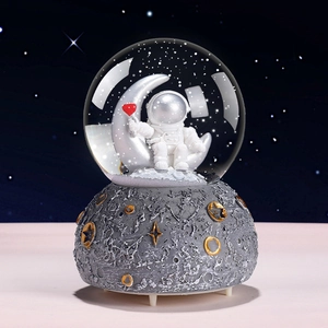 Astronaut snow globe with moon base and glowing stars against a deep starry sky background