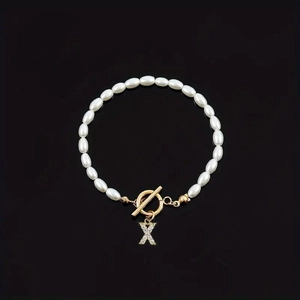 Fashionable white pearl bracelet featuring an oval bead design and a diamond letter X charm