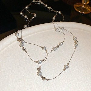 Detail of elegant gold-plated necklace featuring greyish-white pearls and silver metal beads