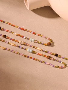 Close-up of colorful faceted zircon beads and tiger eye stone necklace on a textured surface