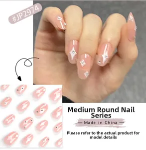 Detail view of pink medium round press-on nails with white starburst and rhinestone accents