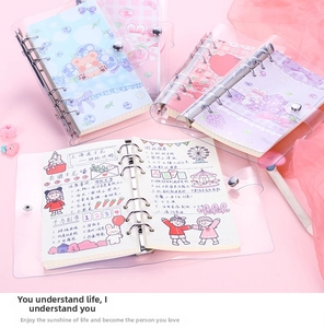 Detail of transparent PVC 6-ring binder with colorful scrapbooking pages and cute covers