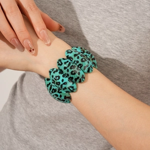 Detail of blue leopard print acrylic bracelet with oval resin links on female wrist