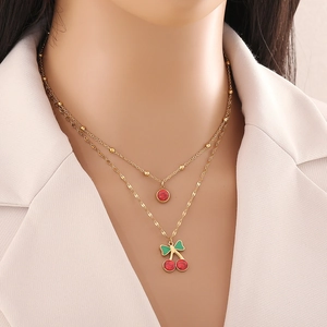 Collier double épaisseur en acier doré avec pendentifs cerise et rouge sur un mannequin