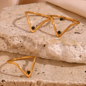 Detailed macro view of three gold V-shaped rings with small black gemstone insets